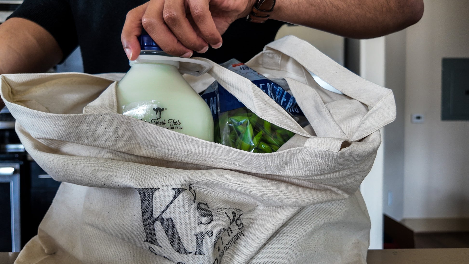 Person holding Ks's Kreole cotton grocery tote bag filled with groceries
