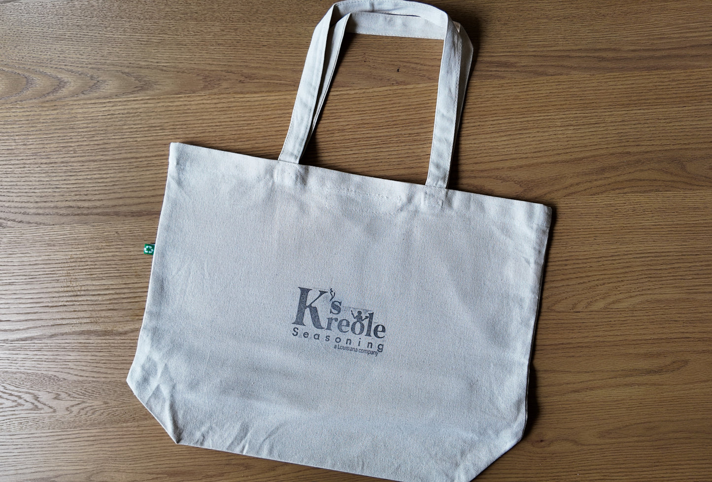 White tote bag with 'K's Kreole' logo on a wooden surface