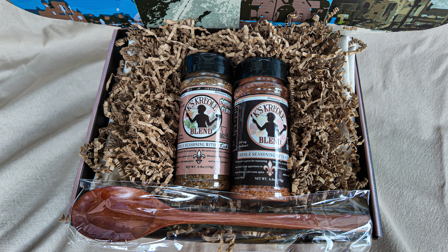 Two bottles of K's Kreole Seasoning with a wooden spoon in a box with brown crinkle paper.